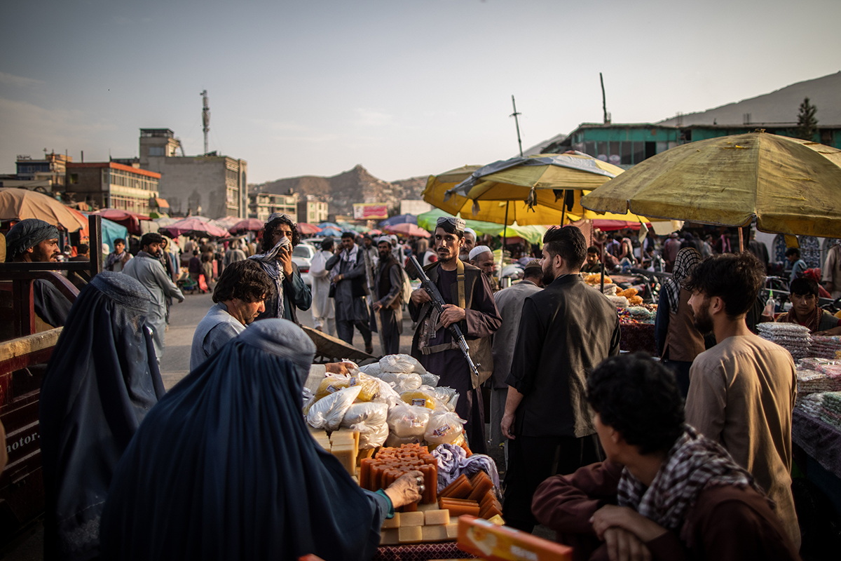 A Taliban fighter stands amid shoppers at a market in Kabul in September 2021. Photo by Oliver Weiken/picture alliance via Getty Images.