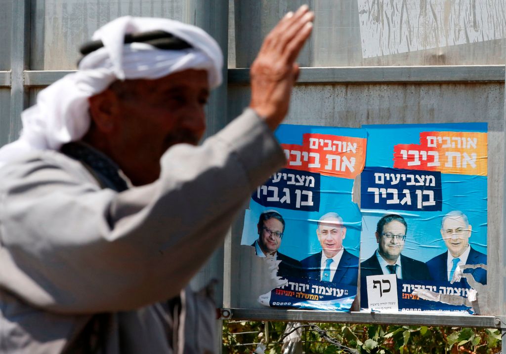 palestinian man in front of israeli election posters