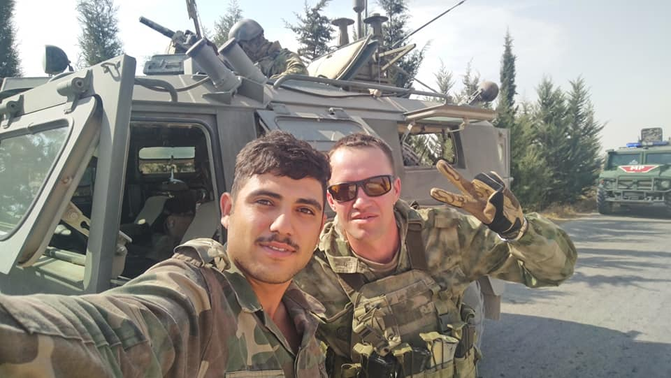 A member of the 106th Brigade poses with a Russian soldier in Manbij, Aleppo