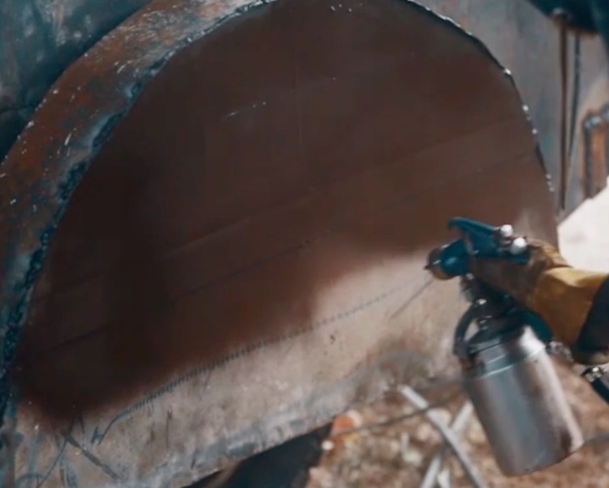 An HTS SVBIED workshop worker applies a brown coat of paint on the vehicle’s standardized armor kit using a spray paint gun.