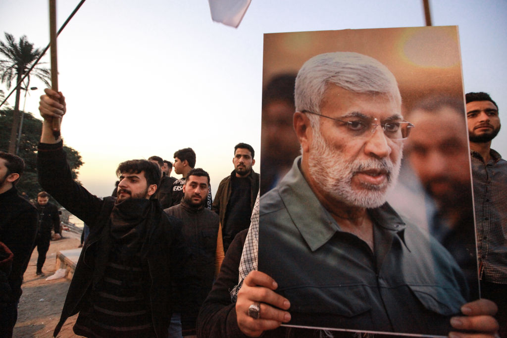 Supporters of the predominantly Shia Muslim Popular Mobilization Forces (PMF) gather with flags and posters of the PMF deputy head Abu Mahdi al-Muhandis during an anti-US protest after the US airstrike in Baghdad