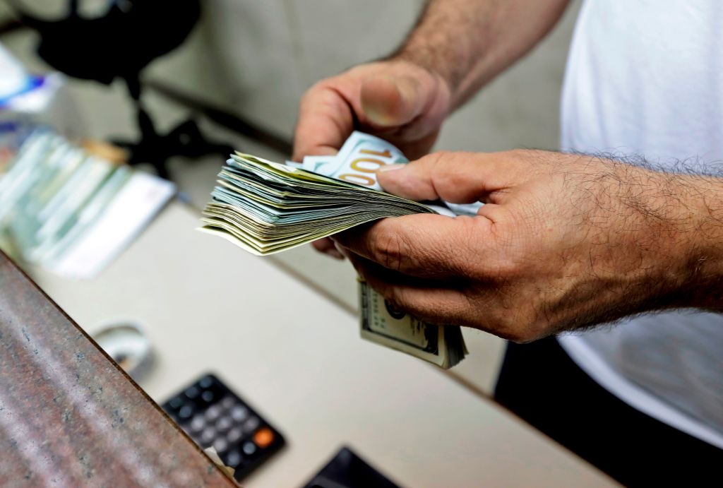 A teller counts US dollars at a currency exchange company in the Lebanese capital Beirut on October 1, 2019. - Lebanon's central bank announced Monday adopting a measure to facilitate access to dollars for importers of petroleum products, wheat, and medicine, state media said Tuesday, following fears of a dollar shortage and possible currency devaluation, in a country which has had a fixed exchange rate of around 1,500 Lebanese pounds to the dollar in place since 1997. (Photo by JOSEPH EID / AFP) (Photo by JOSEPH EID/AFP via Getty Images)