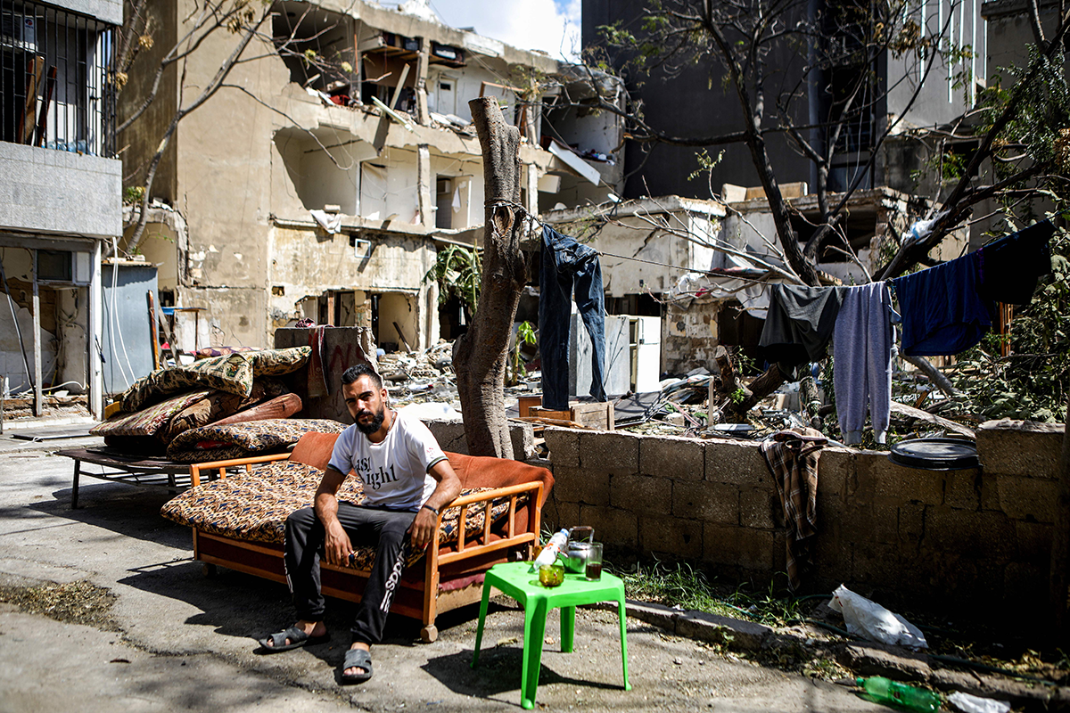 A Syrian refugee from Hama looks on as he sits on his salvaged sofa outside by damaged buildings in the Karantina neighborhood of Beirut on August 9, 2020, in the aftermath of a colossal explosion that occurred days prior at the Port of Beirut. (Photo by PATRICK BAZ/AFP via Getty Images)