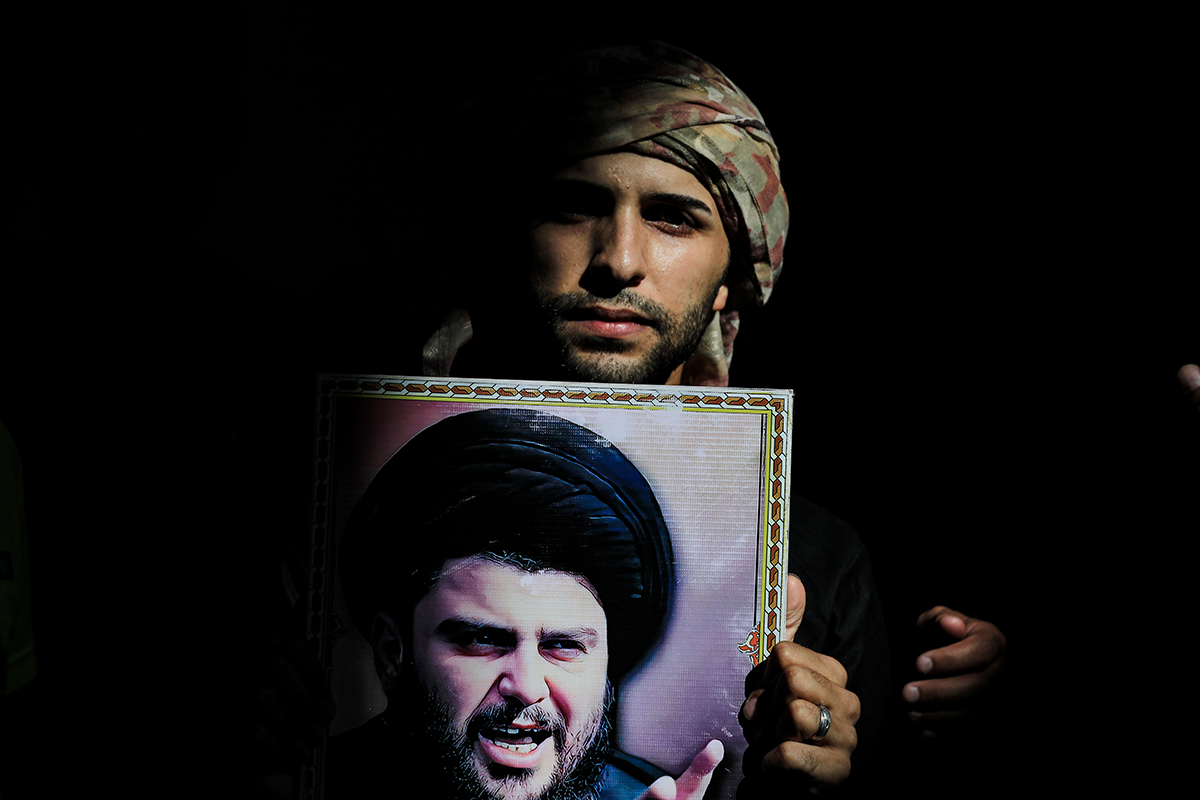 29 August 2022, Iraq, Baghdad: An Iraqi man holds a portrait of Iraqi Shiite cleric Muqtada Al-Sadr during a protest in the grounds of the Government Palace. Followers of al-Sadr headed to the building shortly after the Shiite cleric said he would retire from politics. Photo: Ameer Al-Mohammedawi/dpa (Photo by Ameer Al-Mohammedawi/picture alliance via Getty Images)
