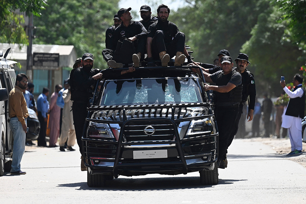Security personnel escort a car carrying former Prime Minister Imran Khan as he arrives at the high court in Islamabad on May 9, 2023, following his arrest. Photo by AAMIR QURESHI/AFP via Getty Images.