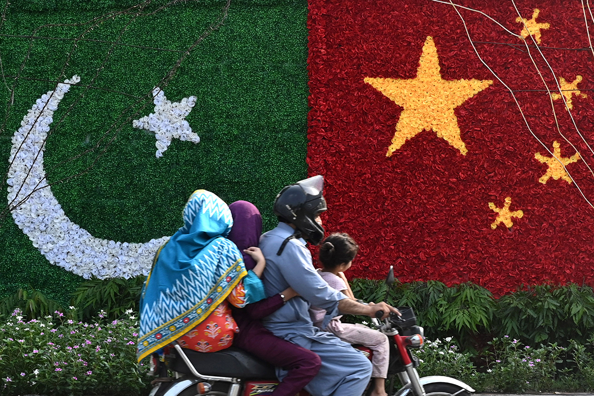 A family rides past a decoration in the shape of the national flags of China and Pakistan installed along a road ahead of the visit of Chinese Vice Premier He Lifeng, in Lahore on July 30, 2023. He was due in the Pakistan capital on July 30 to mark the 10th anniversary of a mega economic plan that is the cornerstone of Beijing's Belt and Road Initiative. (Photo by Arif ALI / AFP) (Photo by ARIF ALI/AFP via Getty Images)