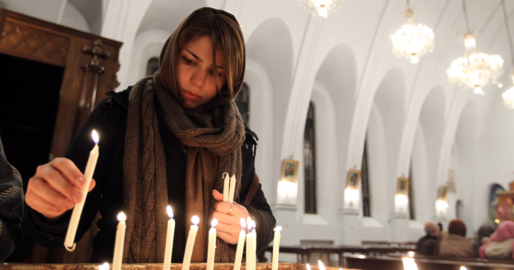 An Iranian Christian woman lights candles during the Christmas Eve mass at the St. Gregor Armenian Catholic church in Tehran on December 24, 201, as Christians around the world are celebrating Christmas. AFP PHOTO/ATTA KENARE        (Photo credit should read ATTA KENARE/AFP via Getty Images)