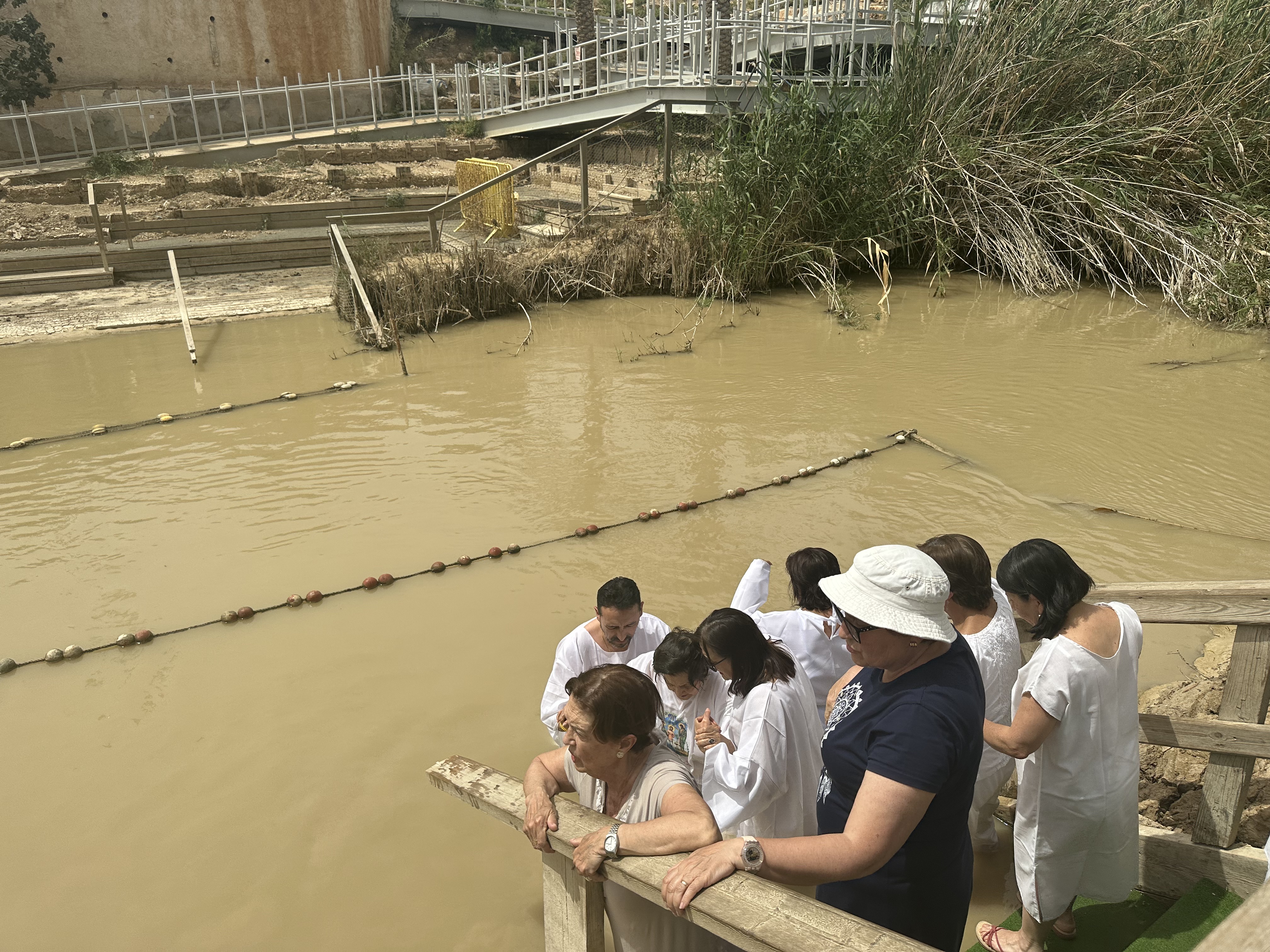 Tourists descending upon the water of the baptism site, observing their surroundings.