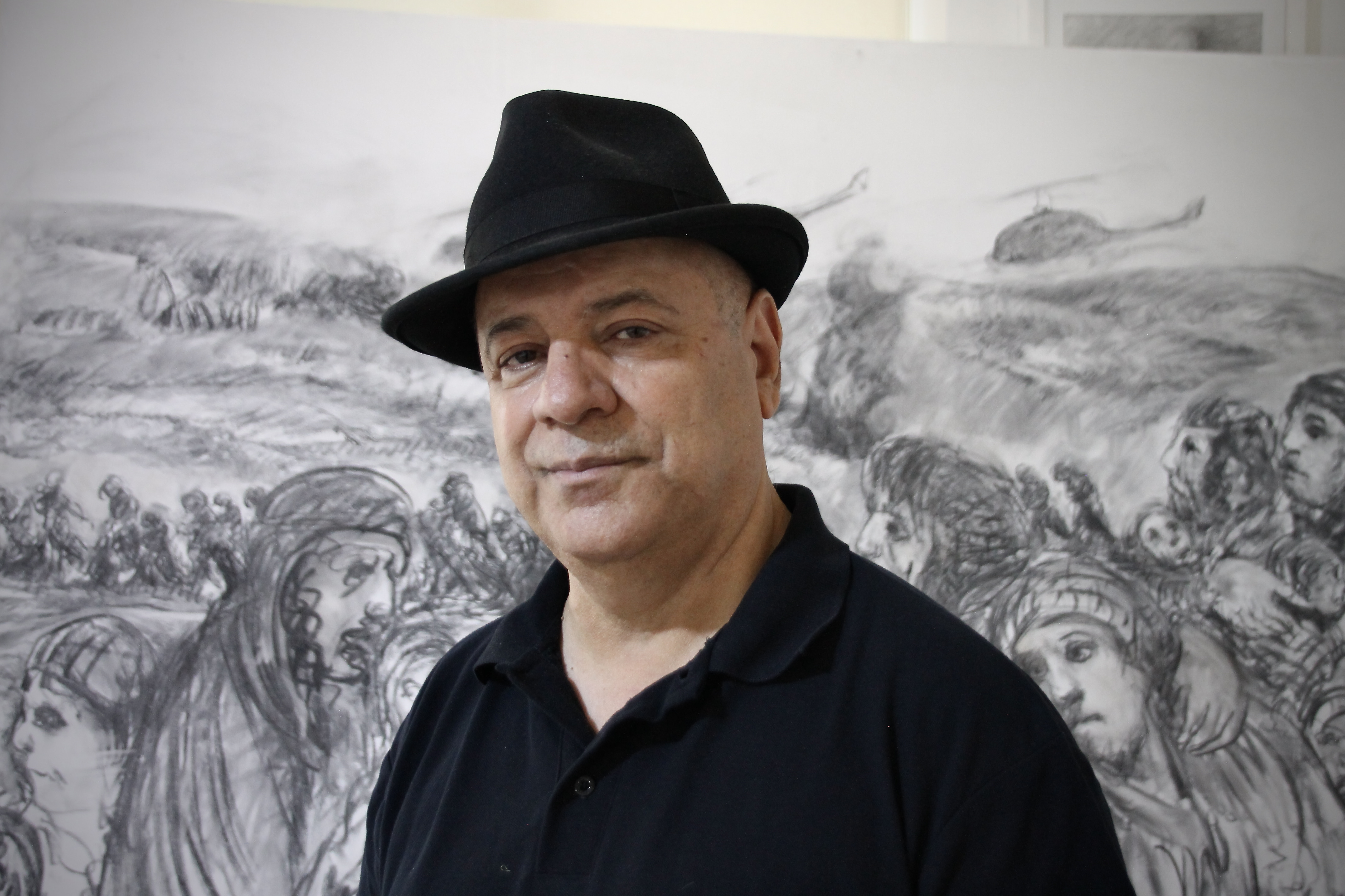 Kurdish artist Osman Ahmed in front of one of his drawings.