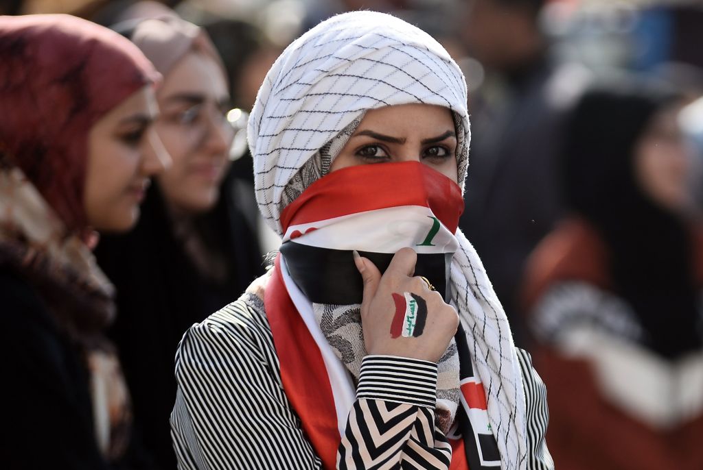 An Iraqi student covers her face with a national flag as she takes part in an anti-government demonstration in the central city of Najaf on December 11, 2019.