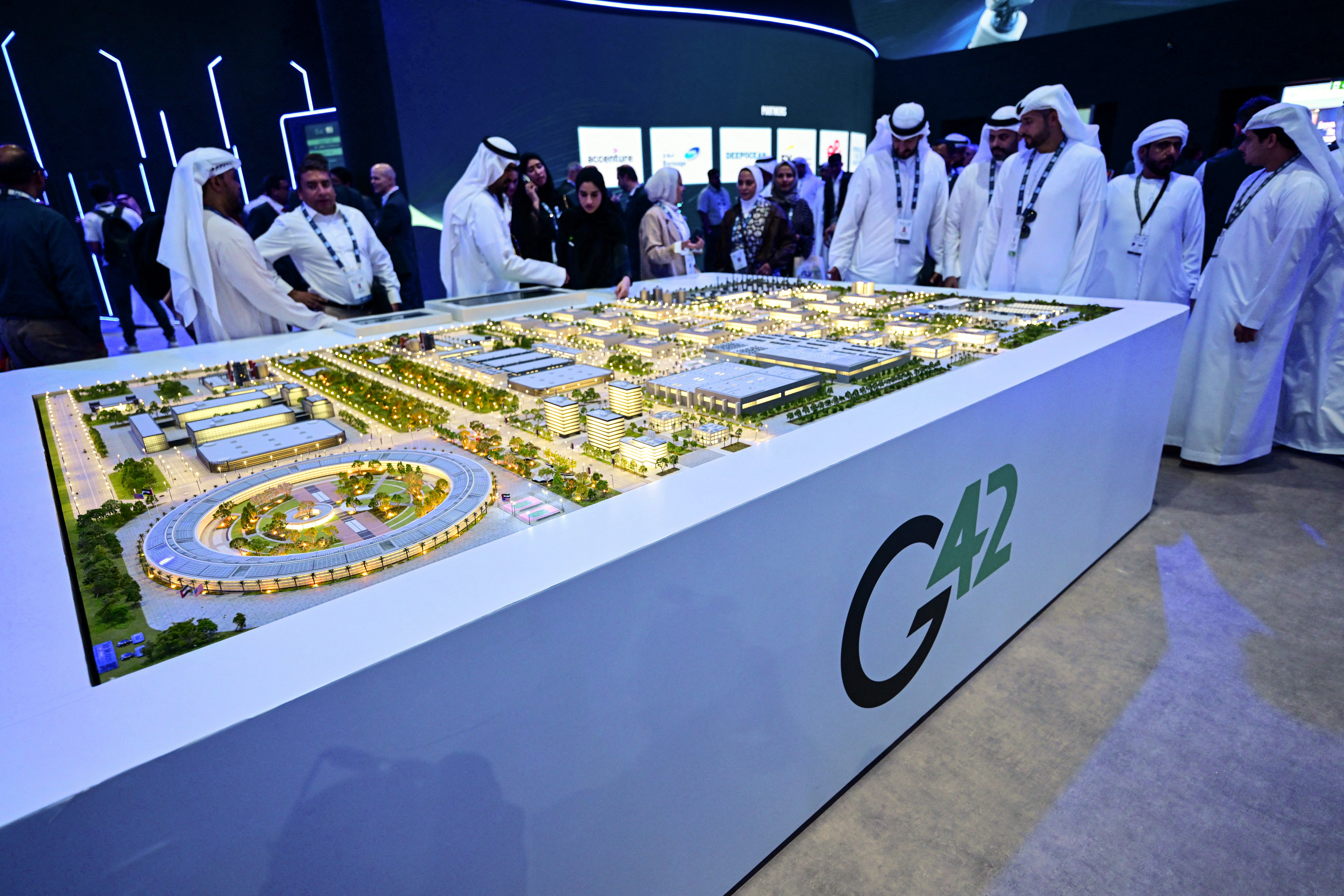 Photo above: Guests look at a model of a data center under construction in the UAE as part of the Stargate initiative, a joint venture between G42, Microsoft, and OpenAI, during the Abu Dhabi International Petroleum Exhibition & Conference (ADIPEC) in Abu Dhabi on November 3, 2025. Photo by Giuseppe Cacace/AFP via Getty Images.[/caption]