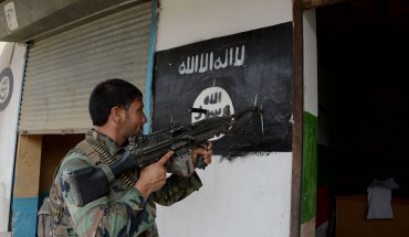 An Afghan soldier points his gun at an ISIS banner as he patrols in Nangarhar Province 