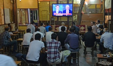 People watch a live broadcast of a televised debate between Istanbul's mayoral candidate Binali Yildirim (R) of Turkey's ruling AKP, and Istanbul's deposed mayor Ekrem Imamoglu (L) of the CHP, is shown on a screen at a tea house in Diyarbakir on June 16, 2019.