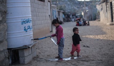 A young Palestinian draws water from a tank