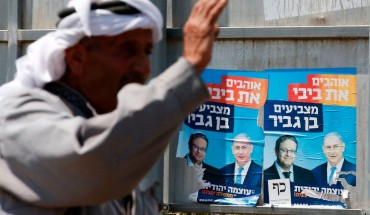 palestinian man in front of israeli election posters
