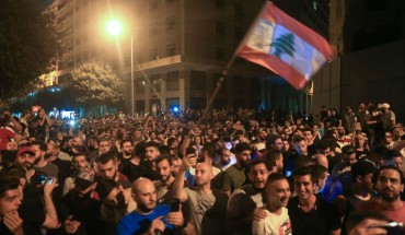 Demonstrators wave a flag during a protest against a government decision to tax calls made on messaging applications on October 17, 2019 outside the government palace in Beirut. 
