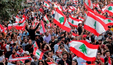 Lebanese protesters wave national flags during demonstrations to demand better living conditions and the ouster of a cast of politicians who have monopolised power and influence for decades, on October 21, 2019 in downtown Beirut. 