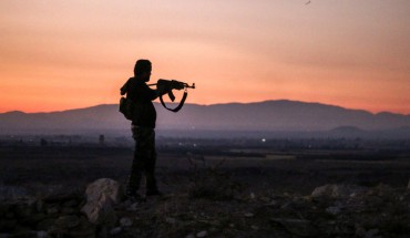 A Syrian rebel fighter aims his Kalashnikov assault rifle as he stands near the frontline against government forces west of the embattled southern city of Daraa on July 3, 2018. 