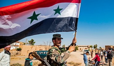  A Syrian regime soldier waves the national flag a street on the western entrance of the town of Tal Tamr in the countryside of Syria's northeastern Hasakeh province on October 14, 2019. 