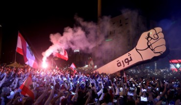 Lebanese demonstrators raise a new giant sign of a fist that bears the Arabic word "revolution" on it, in the Lebanese capital Beirut's Martyr's Square on November 22, 2019, after the sign was burnt overnight by unknown perpetrators.