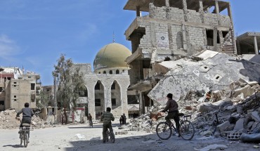 Syrian children ride their bike past destroyed buildings in the former rebel-held town of Zamalka, in Eastern Ghouta on April 5, 2018. / AFP PHOTO / STRINGER (Photo credit should read STRINGER/AFP via Getty Images)