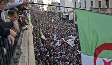  Algerians wave a national flag from a balcony as they watch anti-government demonstrators march in the capital Algiers on December 6, 2019, ahead of the presidential vote scheduled for December 12.