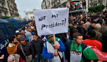 An Algerian protester lifts a placard in the capital Algiers on December 13, 2019, as he takes part in a demonstration to reject the results of the presidential elections. 