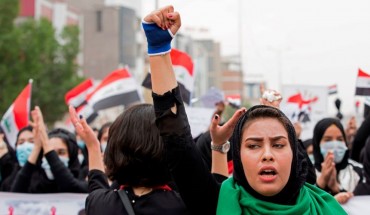 An Iraqi woman raises her fist as she takes part in an anti-government march in the center of the southern city of Basra on December 2, 2019.