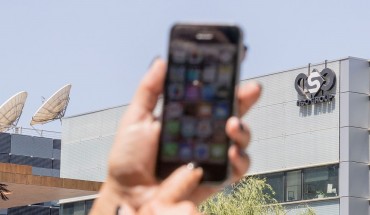 An Israeli woman uses her iPhone in front of the building housing the Israeli NSO group, on August 28, 2016, in Herzliya, near Tel Aviv. 