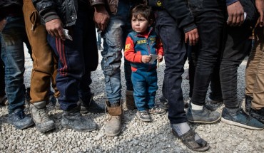 Displaced Syrians wait in a queue as an NGO delivers bread as they wait to receive humanitarian aid in a stadium which has been turned into a makeshift refugee shelter on February 19, 2020 in Idlib, Syria.