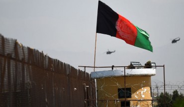 Two US military helicopters are seen flying past an Afghan national flag during the 100th anniversary of the country's Independence Day in Kabul on August 19, 2019. 