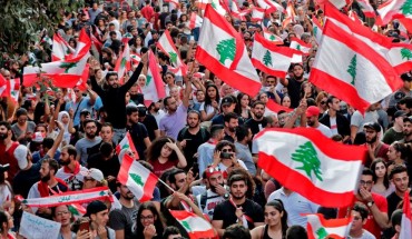 Lebanese protesters wave national flags during demonstrations to demand better living conditions and the ouster of a cast of politicians who have monopolised power and influence for decades, on October 21, 2019 in downtown Beirut. -