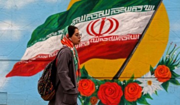 A woman walks past a mural with the Iranian national flag in Tehran, on February 20, 2020 on the eve of parliamentary election. 