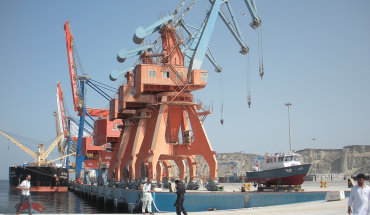 In this photograph taken on October 4, 2017, Pakistani labourers walk through Gwadar port. Remote and impoverished, Pakistan's Gwadar port at first glance seems an unlikely crown jewel in a multi-billion dollar development project with China aimed at constructing a 21st century Silk Road. Situated on a barren peninsula in the Arabian Sea, Gwadar, or the "gate of the wind", owes its fortuitous selection as Pakistan's next economic hub to its strategic location near the Strait of Hormuz. 