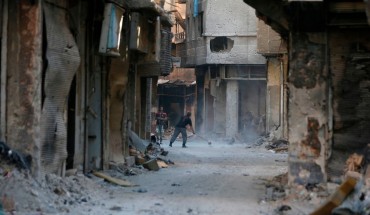 A man cleans in a street near destroyed buildings in the Palestinian camp of Yarmuk southern Damascus on November 1, 2018. - Former residents of the Palestinian camp of Yarmuk are desperately counting on help from abroad to help raise the once-bustling neighbourhood back out of the rubble.