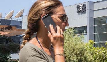 An Israeli woman uses her iPhone in front of the building housing the Israeli NSO group, on August 28, 2016, in Herzliya, near Tel Aviv. 