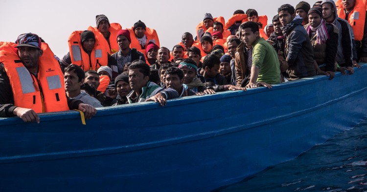 Migrants and refugees are assisted by members of the Spanish NGO Proactiva Open Arms as they crowd on board of a wooden boat sailing out of control at 20 miles (38 km) north of Sabratha, Libya on February 18, 2017.