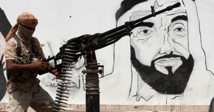 A picture taken on August 8, 2018 during a trip in Yemen organised by the UAE's National Media Council (NMC) shows a soldier loyal to the Saudi and UAE-backed government, manning a machine gun mounted on a vehicle passing by a mural depicting the late UAE founder and president Sheikh Zayed bin Sultan al-Nahyan, along a street in the southeastern port city of Mukalla, the capital of Hadramawt province. 