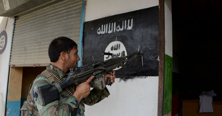 An Afghan soldier points his gun at an ISIS banner as he patrols in Nangarhar Province 