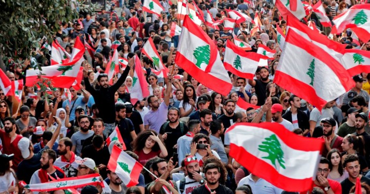 Lebanese protesters wave national flags during demonstrations to demand better living conditions and the ouster of a cast of politicians who have monopolised power and influence for decades, on October 21, 2019 in downtown Beirut. 