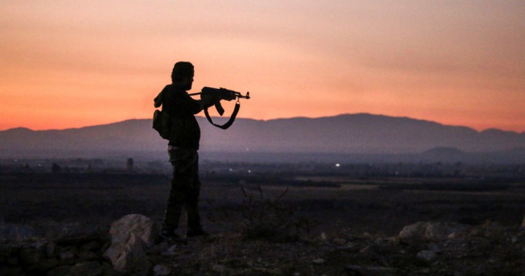 A Syrian rebel fighter aims his Kalashnikov assault rifle as he stands near the frontline against government forces west of the embattled southern city of Daraa on July 3, 2018. 