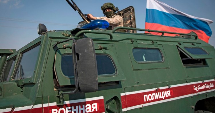 A soldier rides atop a Russian military vehicle near the Syrian northeastern city of Qamishli on October 26, 2019. 