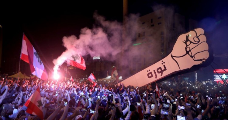 Lebanese demonstrators raise a new giant sign of a fist that bears the Arabic word "revolution" on it, in the Lebanese capital Beirut's Martyr's Square on November 22, 2019, after the sign was burnt overnight by unknown perpetrators.