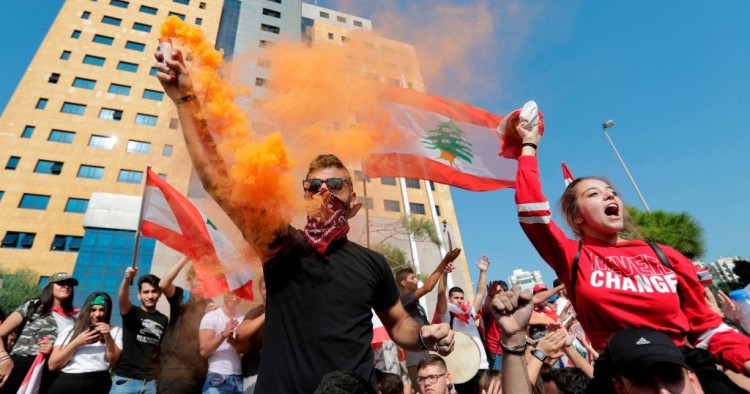 Lebanese students wave the national flag and chant slogans as they gather outside the Ministry of Education and Higher Education during ongoing anti-government protests, in the capital Beirut on November 8, 2019.
