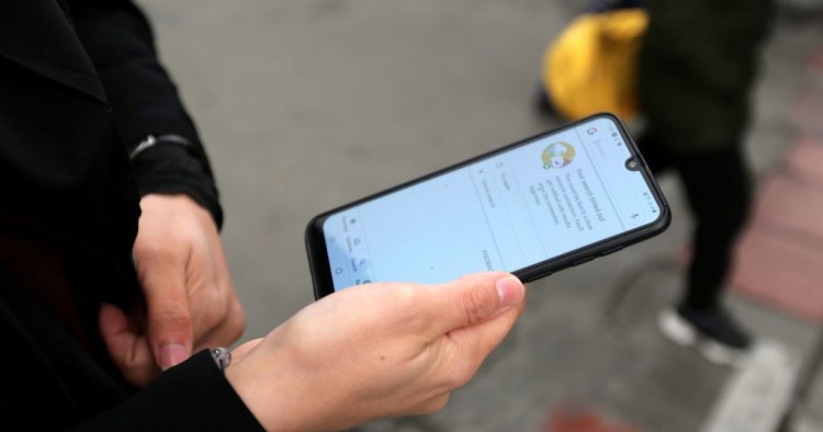 A woman holds a smartphone shown to be unable to access internet, while standing along a street in the Iranian capital Tehran on November 23, 2019. 