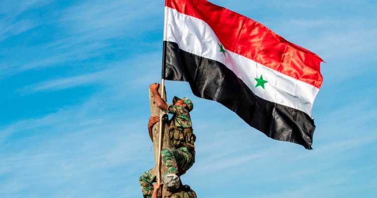 Syrian government soldiers climb up a wooden pole with a Syrian government national flag while deploying for the first time in the eastern countryside of the city of Qamishli in the northeastern Hasakah province on November 5, 2019.