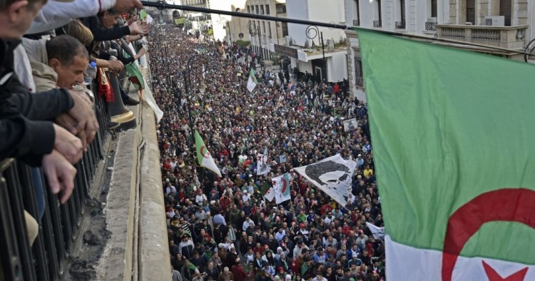  Algerians wave a national flag from a balcony as they watch anti-government demonstrators march in the capital Algiers on December 6, 2019, ahead of the presidential vote scheduled for December 12.