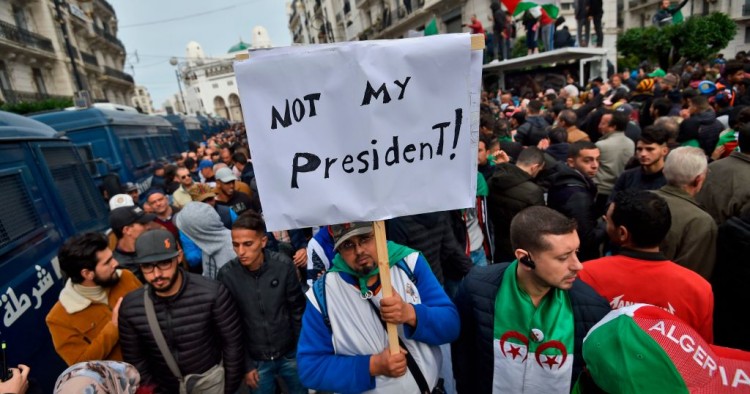 An Algerian protester lifts a placard in the capital Algiers on December 13, 2019, as he takes part in a demonstration to reject the results of the presidential elections. 