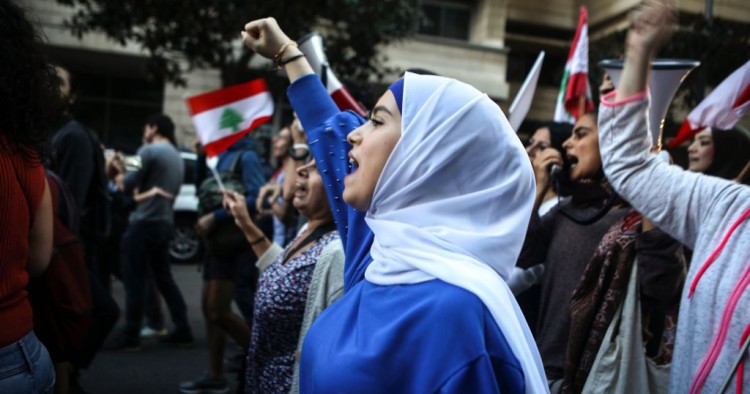 Lebanese anti-government protesters shout slogans as they march on the former demarcation line separating Beirut on December 1, 2019. 