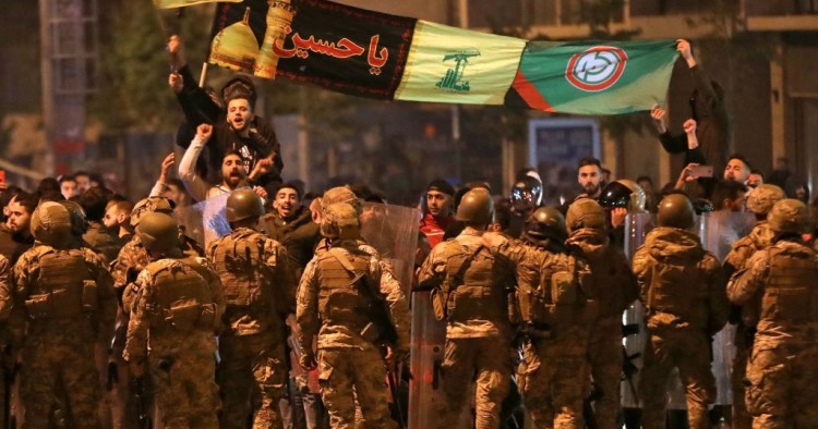 Supporters of Lebanese Shiite groups Hezbollah and Amal wave flags and chant in front of army soldiers in the capital Beirut, on November 25, 2019.